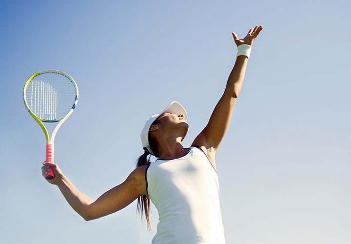 Woman serving tennis after laser hair removal